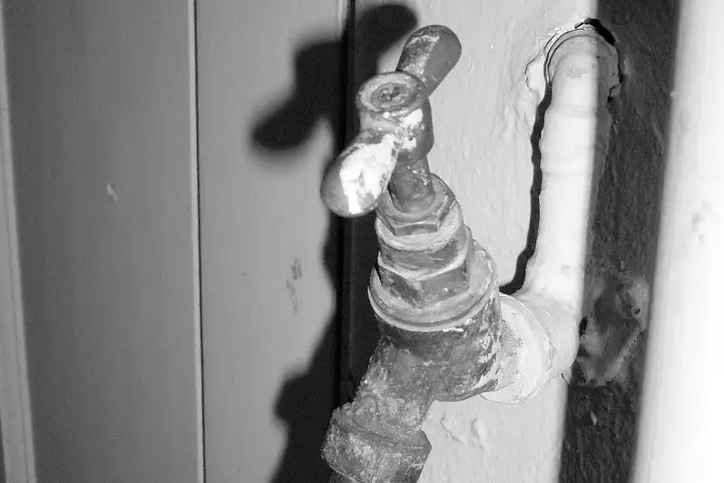 Grifo exterior en una pared cubierto de hielo, en blanco y negro