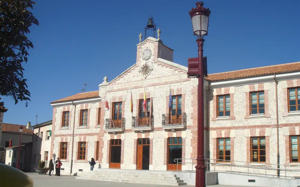 Edificio del Ayuntamiento de Villagonzalo Pedernales, de dos plantas con reloj y balcones, y una farola en primer plano